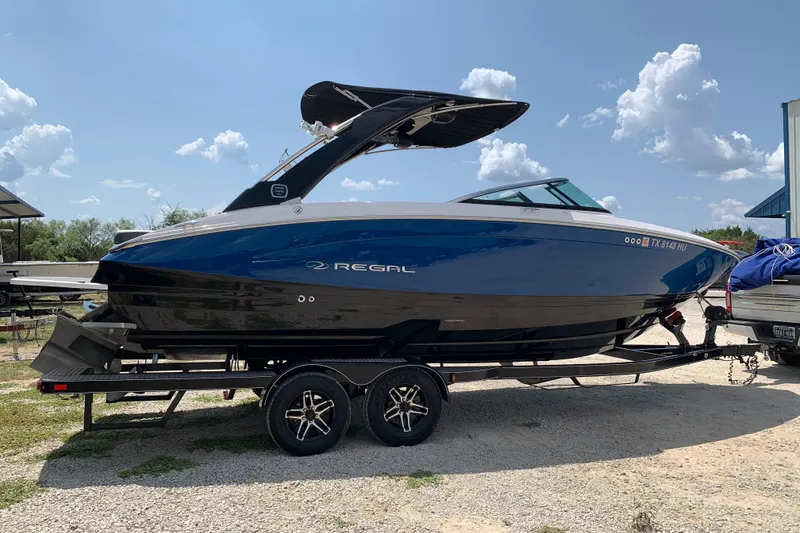 Slide: The Image of 2020 Regal LS6 Surf boat on trailer under a clear blue sky. - 1