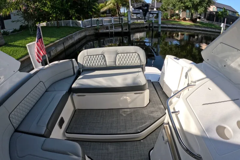 Slide: The Image of 2017 Monterey 295 Sport Yacht interior with elegant seating and American flag, docked by lush greenery. - 32