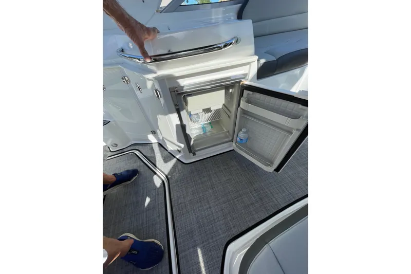 Slide: The Image of Open mini fridge on 2017 Monterey 295 Sport Yacht, showing bottled water inside. - 23