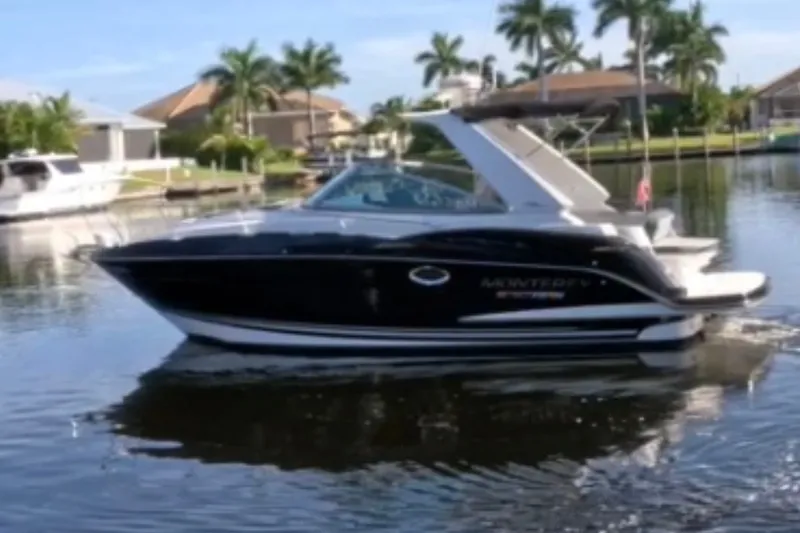 Slide: The Image of 2017 Monterey 295 Sport Yacht cruising on a calm, scenic waterway with palm trees. - 31