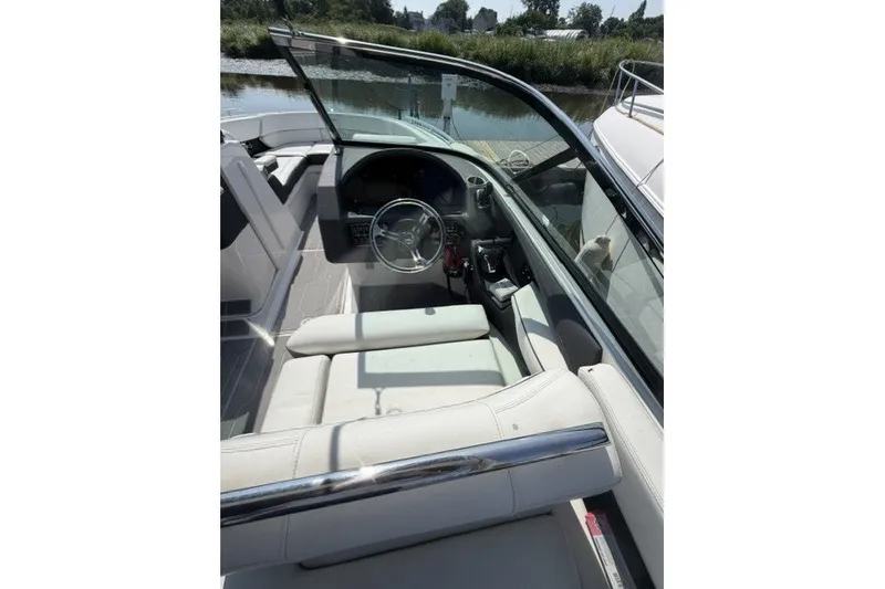 Slide: The Image of 2023 Regal 29 OBX boat interior with steering wheel and seating, docked by a calm river. - 24