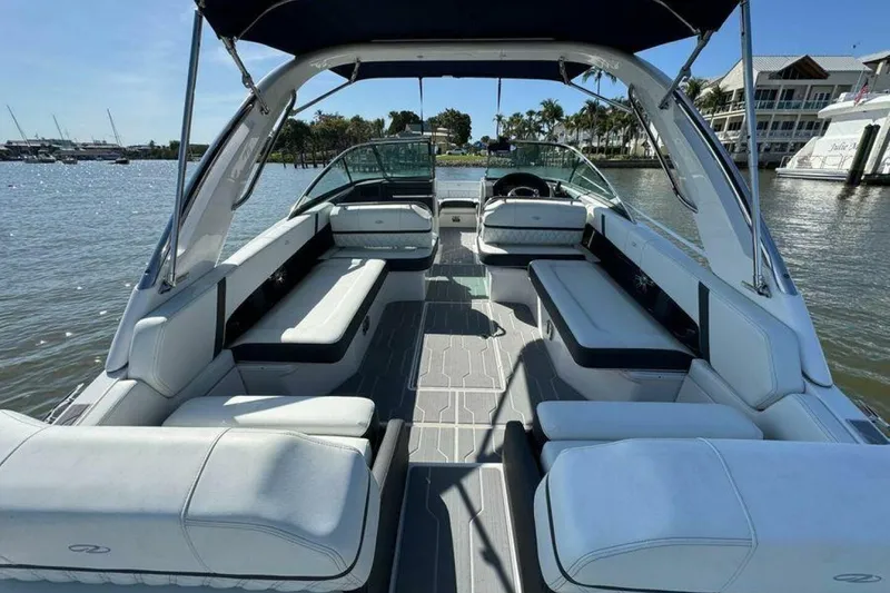 Slide: The Image of 2023 Regal 29 OBX boat interior with spacious seating, docked by waterfront homes. - 16