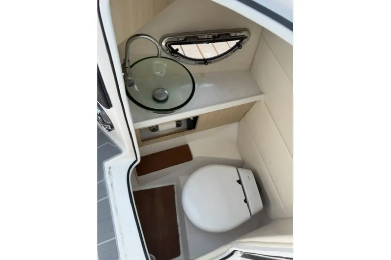 Slide: The Image of 2023 Regal 29 OBX boat interior with compact bathroom, featuring a toilet and glass sink. - 15