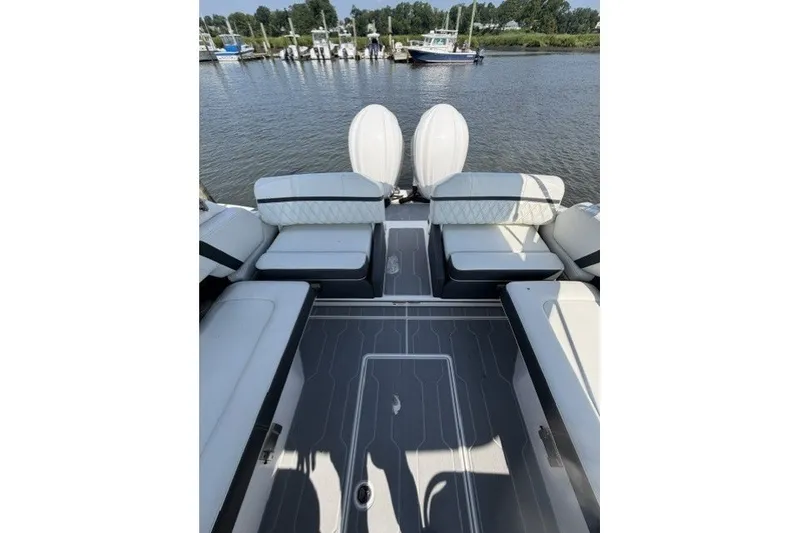Slide: The Image of 2023 Regal 29 OBX boat interior with seating, docked by a calm river. - 27