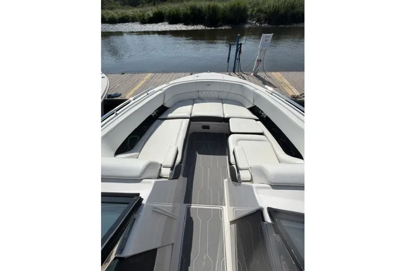 Slide: The Image of 2023 Regal 29 OBX boat interior with white seating and gray flooring, docked by water. - 23