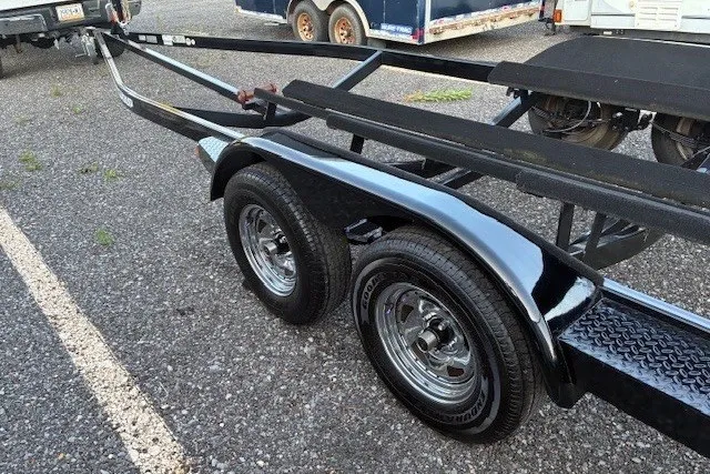 Slide: The Image of Trailer for 2009 Baja 24 H2X Boss boat with dual axles on gravel surface. - 44