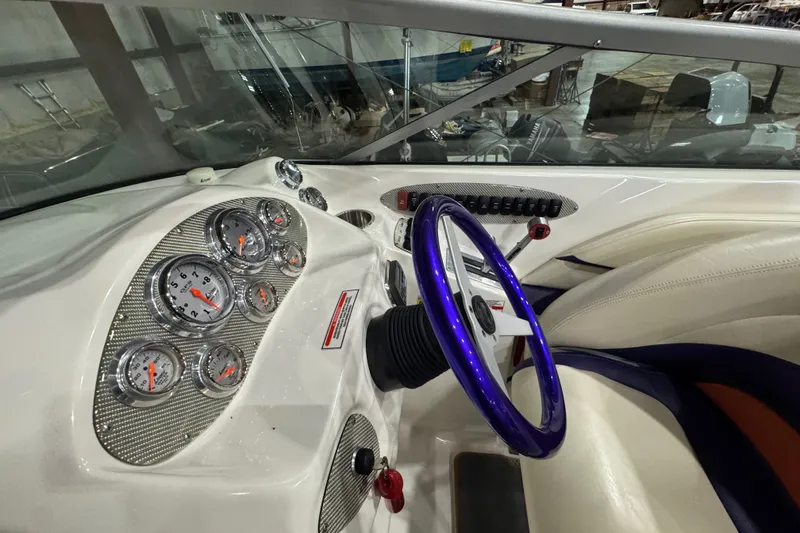 Slide: The Image of Interior dashboard of a 2009 Baja 24 H2X Boss boat with gauges and purple steering wheel. - 41