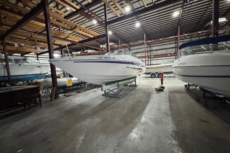 Slide: The Image of 2009 Baja 24 H2X Boss boat stored indoors, surrounded by other vessels. - 16