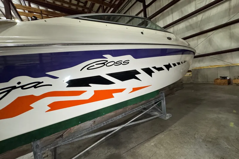 Slide: The Image of 2009 Baja 24 H2X Boss boat with vibrant graphics in a storage facility. - 17