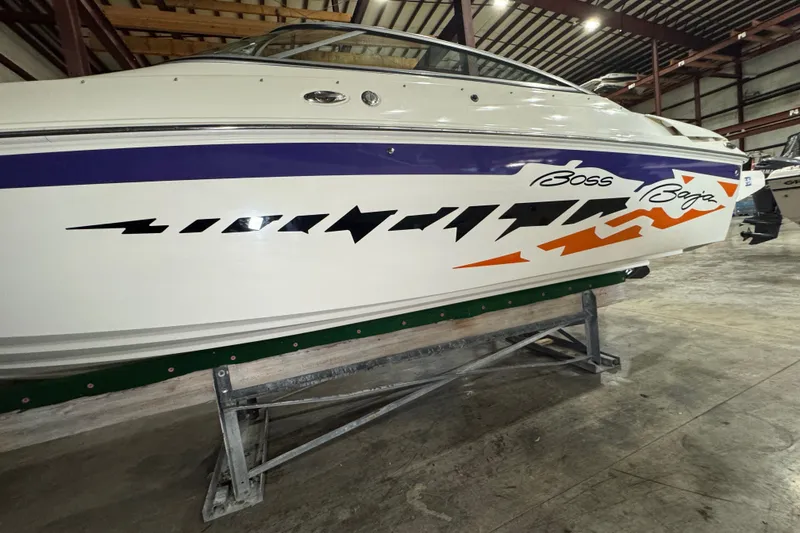 Slide: The Image of 2009 Baja 24 H2X Boss boat with vibrant graphics in a storage facility. - 21
