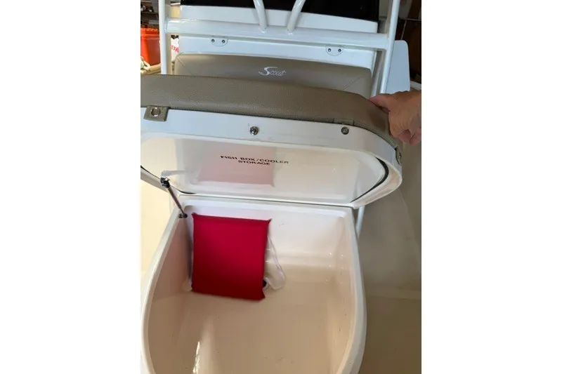 Slide: The Image of 2020 Scout 215 XSF boat's fish box cooler storage with open lid and red cushion. - 20