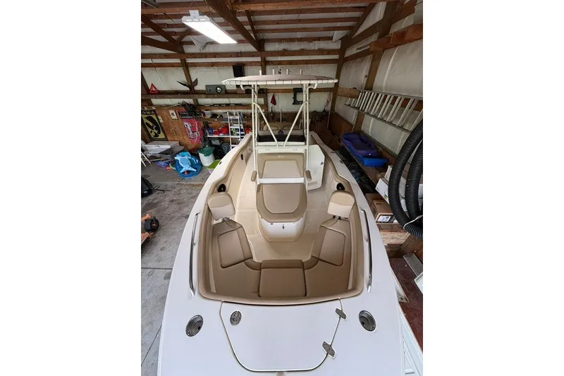 Slide: The Image of 2020 Scout 215 XSF boat in a garage, featuring beige seating and a T-top. - 16