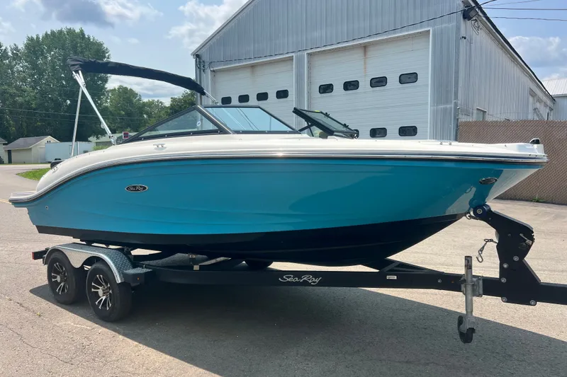 Slide: The Image of 2023 Sea Ray SPX 190 boat on trailer, blue hull, parked outside industrial building. - 29
