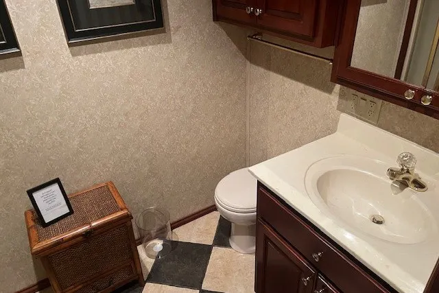 Slide: The Image of Small bathroom with wooden cabinets, checkered floor, and decorative framed art. - 39