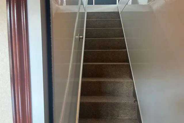 Slide: The Image of Narrow carpeted staircase with white walls, viewed from the bottom, in a residential setting. - 23