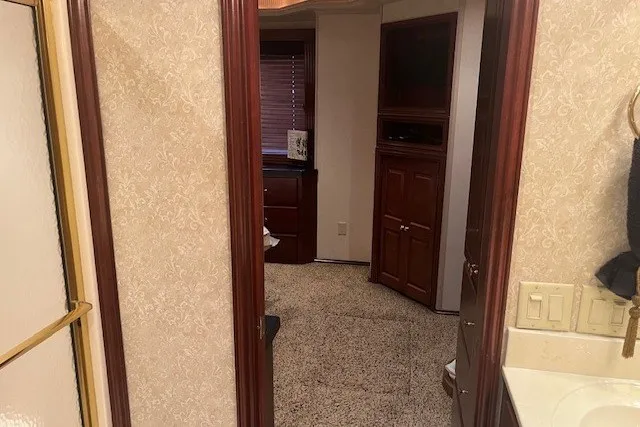 Slide: The Image of Interior view of a 2006 Fantasy 20x100 RV, featuring a cozy carpeted hallway and wooden cabinetry. - 54