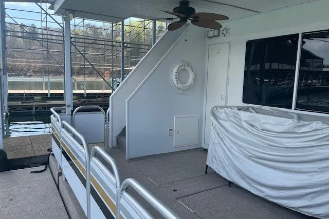 Slide: The Image of Houseboat deck with covered seating, railing, and life preserver, docked at a marina. - 61