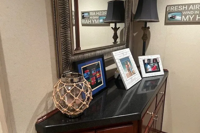 Slide: The Image of Decorative hallway with framed photos, nautical lamp, and mirror on a black countertop. - 29