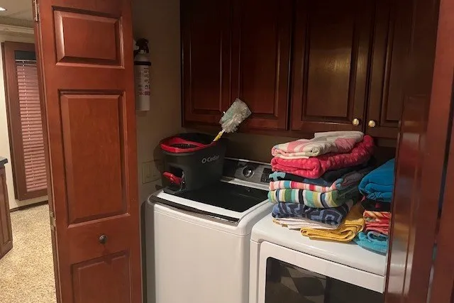 Slide: The Image of Laundry room with stacked towels, washer, dryer, and cleaning supplies in a wooden cabinet setting. - 32