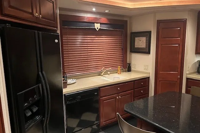 Slide: The Image of Luxurious kitchen with dark wood cabinets, black appliances, and granite countertops in a 2006 Fantasy model. - 13