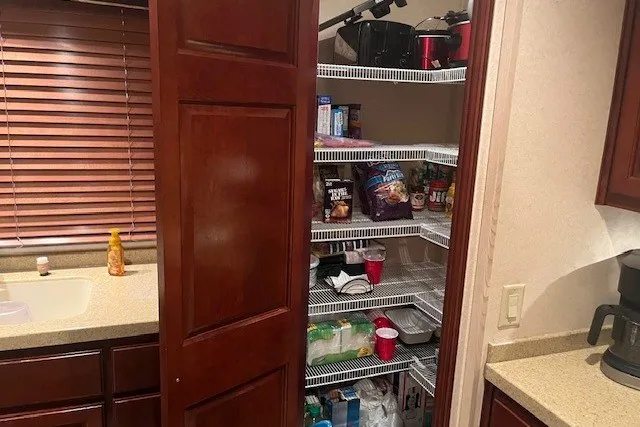 Slide: The Image of A kitchen pantry with open wooden door, revealing shelves stocked with various food items. - 14