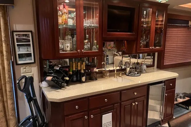 Slide: The Image of Luxurious home bar with wooden cabinets, glassware, and a countertop featuring a sink and wine bottles. - 20