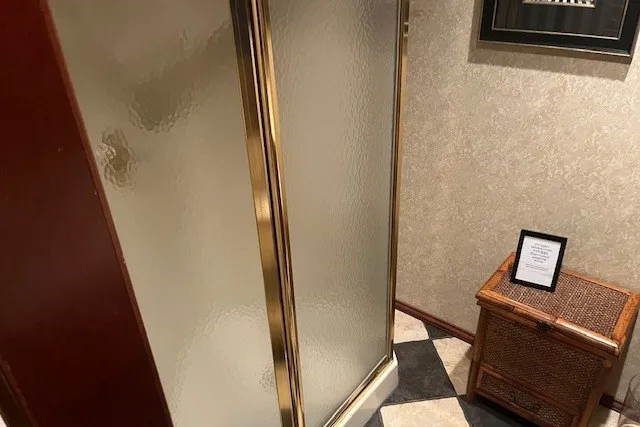 Slide: The Image of Compact bathroom with gold-framed shower, wicker cabinet, and patterned floor tiles. - 38