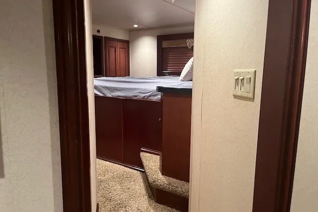 Slide: The Image of Interior view of a 2006 Fantasy 20x100 RV bedroom with elevated bed and carpeted steps. - 35