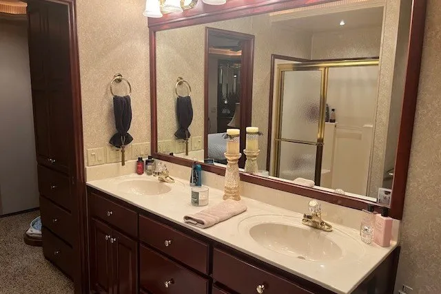 Slide: The Image of Elegant bathroom with double sinks, large mirror, and wooden cabinetry, featuring a glass shower enclosure. - 51