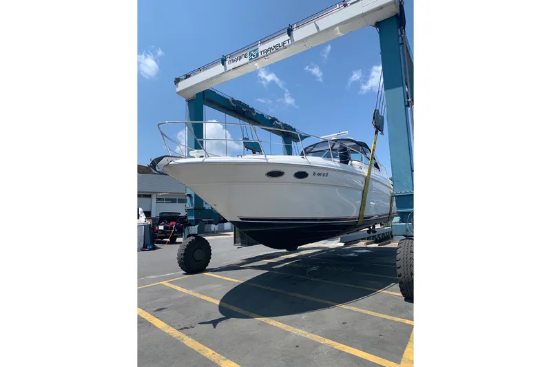 Slide: The Image of 2003 Sea Ray 380 Sundancer yacht lifted by a marine travel lift at a dockyard. - 2