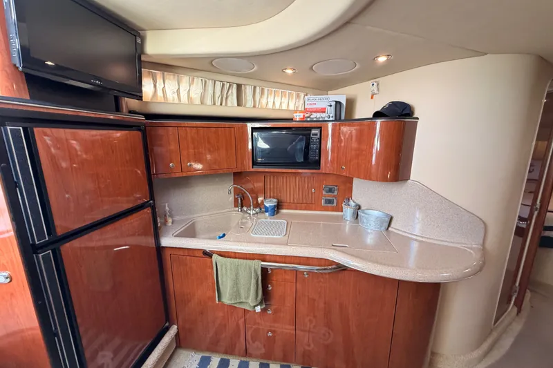 Slide: The Image of 2003 Sea Ray 380 Sundancer yacht kitchen with wood cabinets, microwave, and sink. - 19