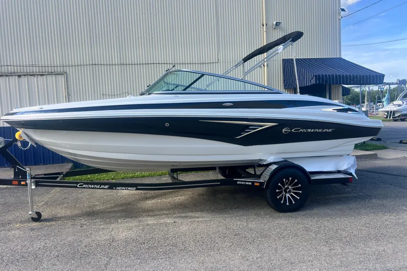 Slide: The Image of 2027 Crownline 200 SS boat on trailer, parked outdoors near a building. - 6