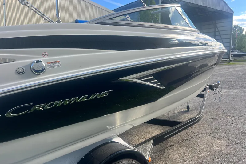 Slide: The Image of 2027 Crownline 200 SS boat on trailer, parked outdoors near a building. - 5