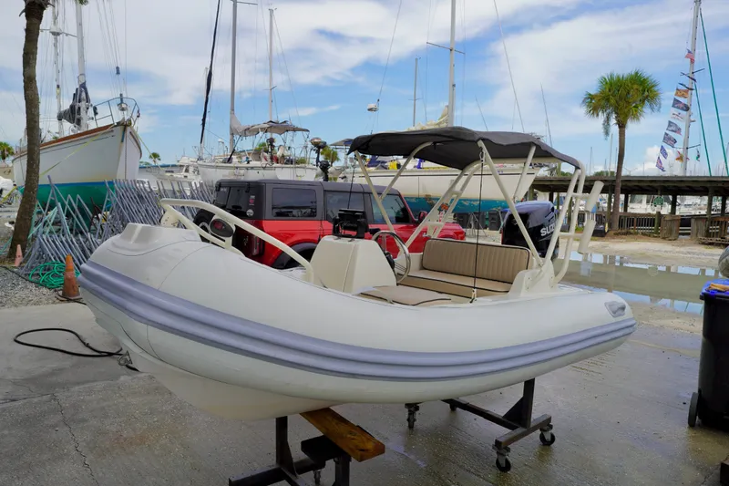 The Image of 2002 AB Inflatables Nautilus 11 DLX boat on stand, marina background, palm trees, and sailboats. - 0