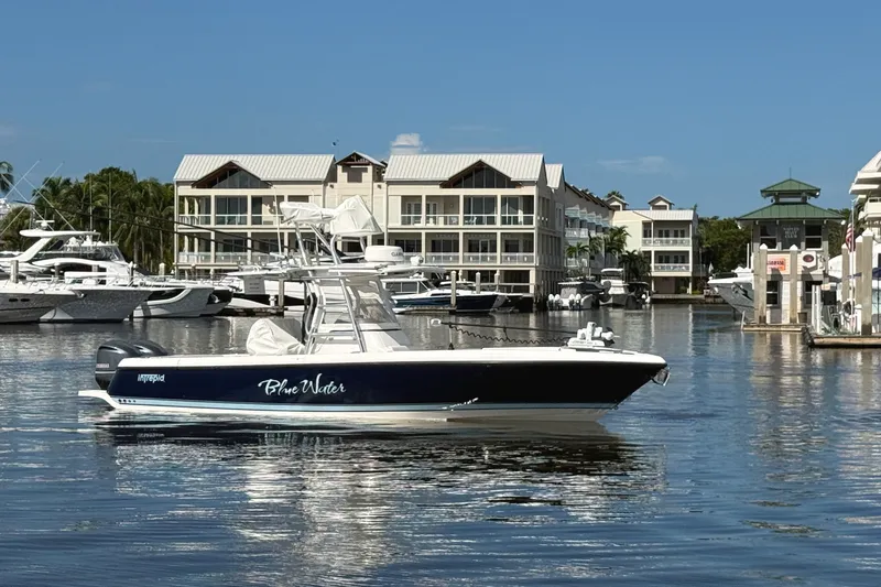Slide: The Image of 2014 Intrepid 327 Center Console boat docked in a marina with waterfront buildings. - 1