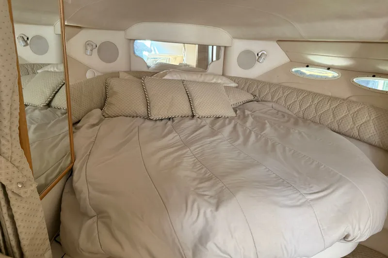 Slide: The Image of Cozy cabin interior of 2000 Sea Ray 340 Sundancer with plush bedding and porthole windows. - 17