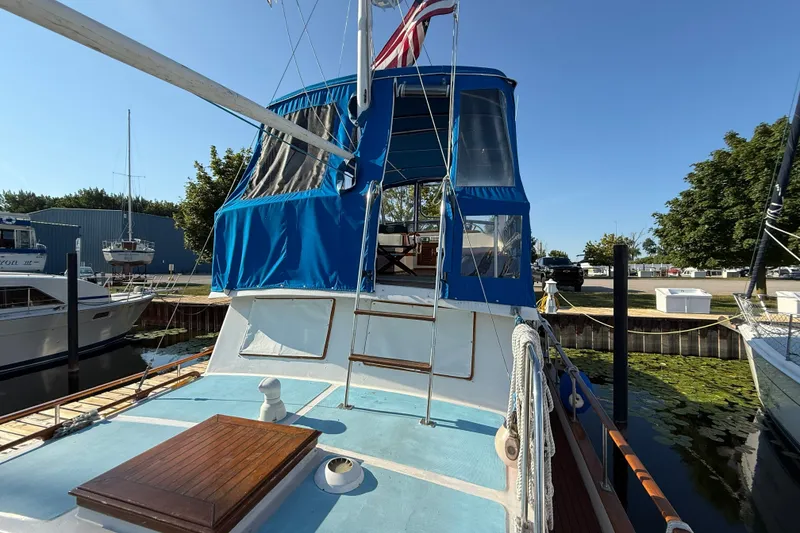 Slide: The Image of 1982 Albin 36 Trawler docked, featuring blue canopy and wooden deck details. - 9