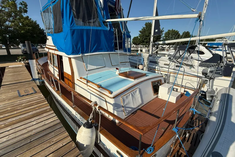 Slide: The Image of 1982 Albin 36 Trawler docked, featuring blue canopy and wooden deck, in a marina setting. - 8