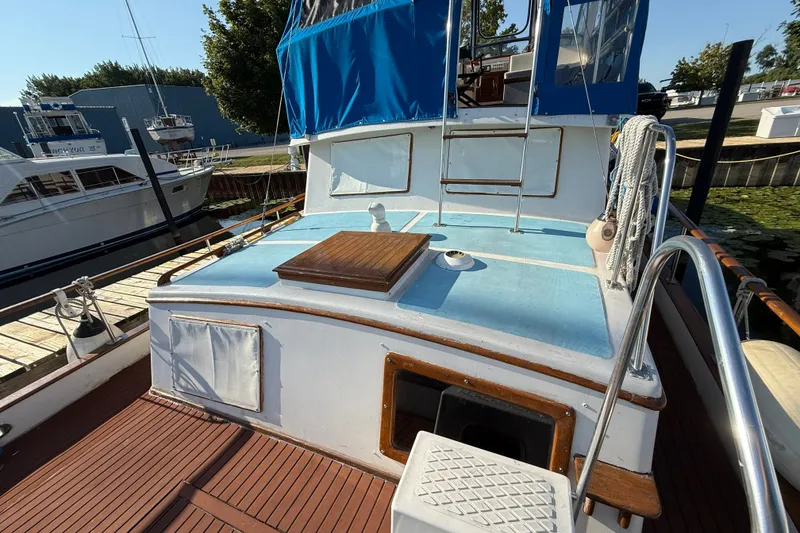 Slide: The Image of 1982 Albin 36 Trawler with blue canopy, docked at marina, showcasing deck and cabin entrance. - 10