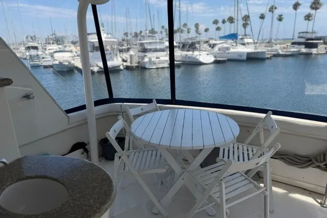 Slide: The Image of 1997 Maxum 4100 SCA yacht with white deck furniture, overlooking marina with boats and palm trees. - 15