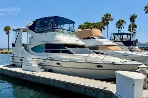 The Image of 1997 Maxum 4100 SCA yacht docked at marina, clear sky, palm trees in background. - 0