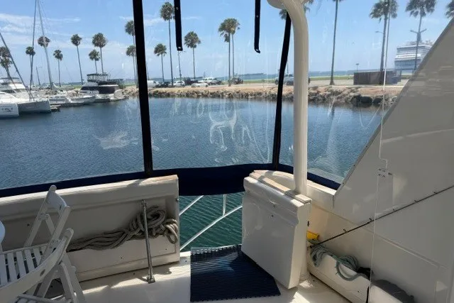 Slide: The Image of 1997 Maxum 4100 SCA yacht interior with marina view, featuring seating and palm trees. - 16