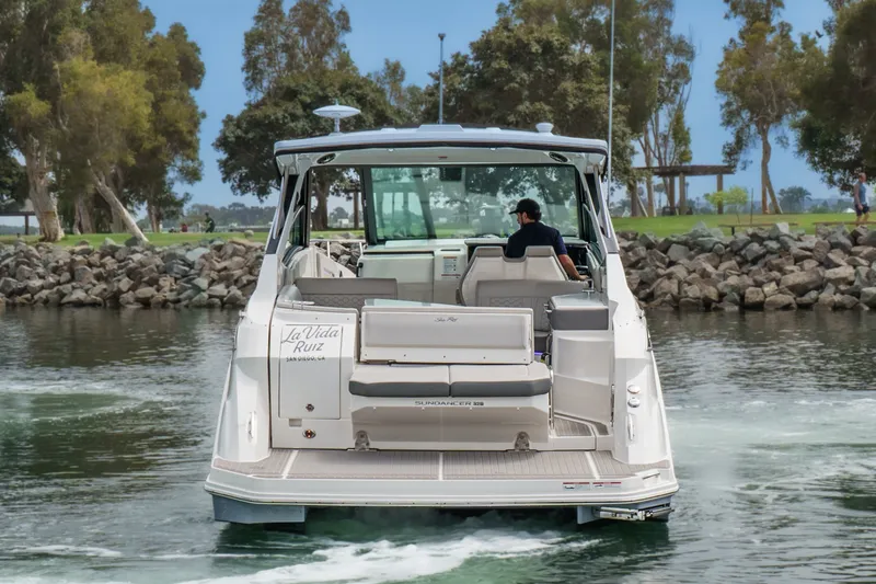 Slide: The Image of The 2025 Sea Ray 320 Sundancer DA Coupe navigates calm waters, surrounded by trees. - 1