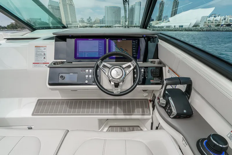 Slide: The Image of The cockpit of the 2025 Sea Ray 320 Sundancer DA Coupe features a modern helm with multiple screens and a sleek steering wheel. - 11
