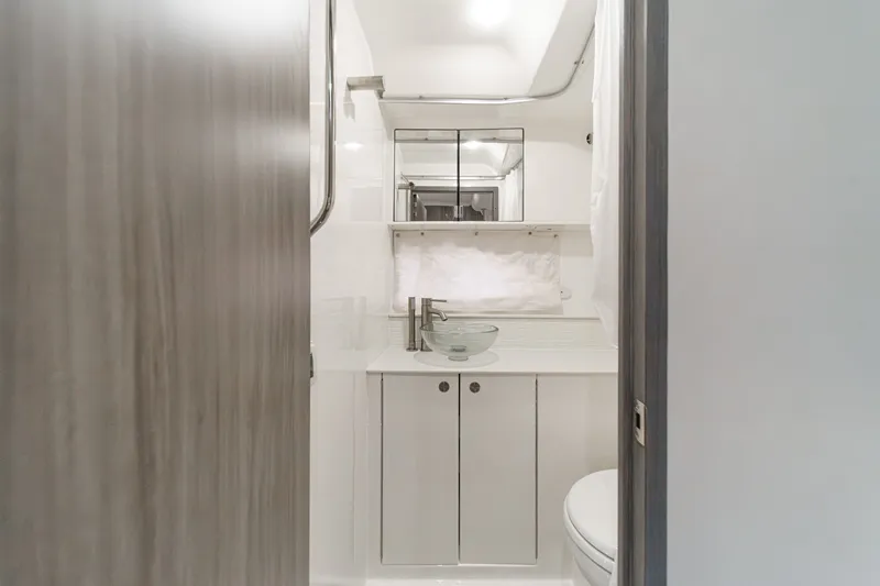 Slide: The Image of The image shows a modern boat bathroom with a sink, mirrors, and storage space. - 30