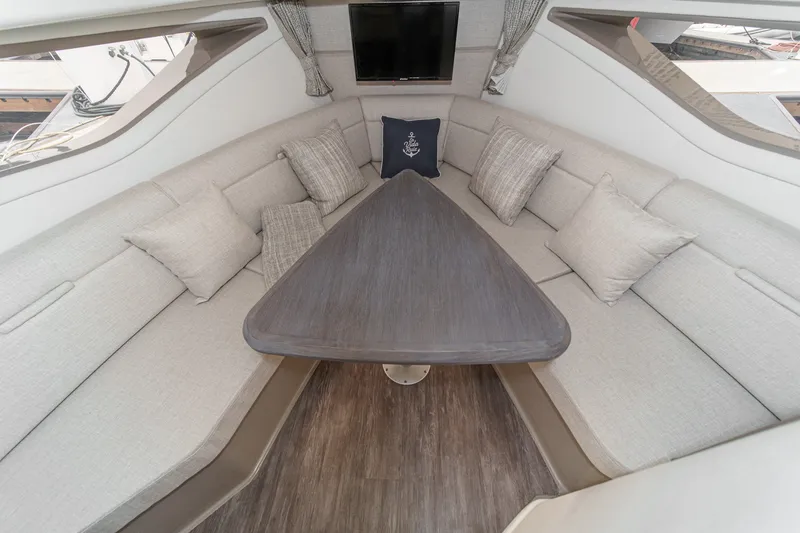 Slide: The Image of The interior of the 2025 Sea Ray 320 Sundancer DA Coupe features an elegant seating area with a triangular table and comfortable cushions. - 22