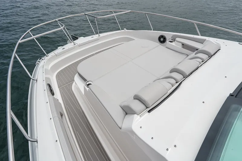Slide: The Image of The image shows the foredeck of a 2025 Sea Ray 320 Sundancer DA Coupe. It features a large cushioned sun pad and stainless steel railings. - 16