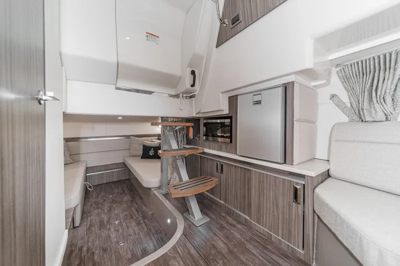 Slide: The Image of Interior of a modern yacht with wood flooring, seating area, microwave, and refrigerator. - 25
