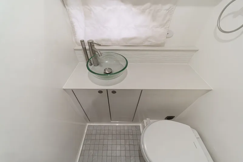 Slide: The Image of The image shows a modern boat bathroom with a glass sink and a toilet. - 31