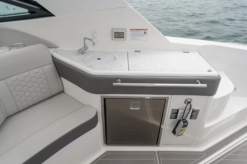 Slide: The Image of The 2025 Sea Ray 320 Sundancer DA Coupe features a sleek outdoor kitchenette with a sink and fridge. - 5